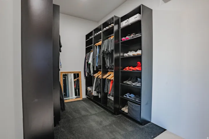 Built-in closet system with shelving, hanging rods, and dark carpeting
