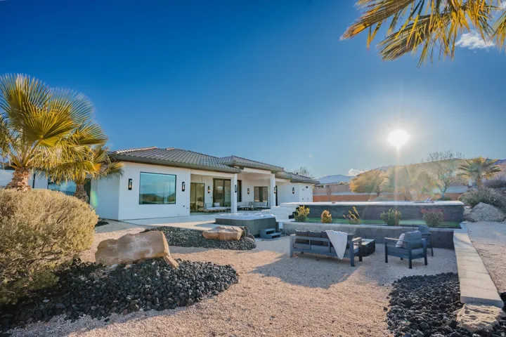 Contemporary architecture featuring large windows, a tiled roof, an integrated spa, and desert landscaping with decorative rock