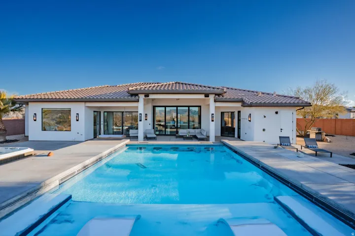 Exterior with a full-width patio, a large swimming pool, and a spa