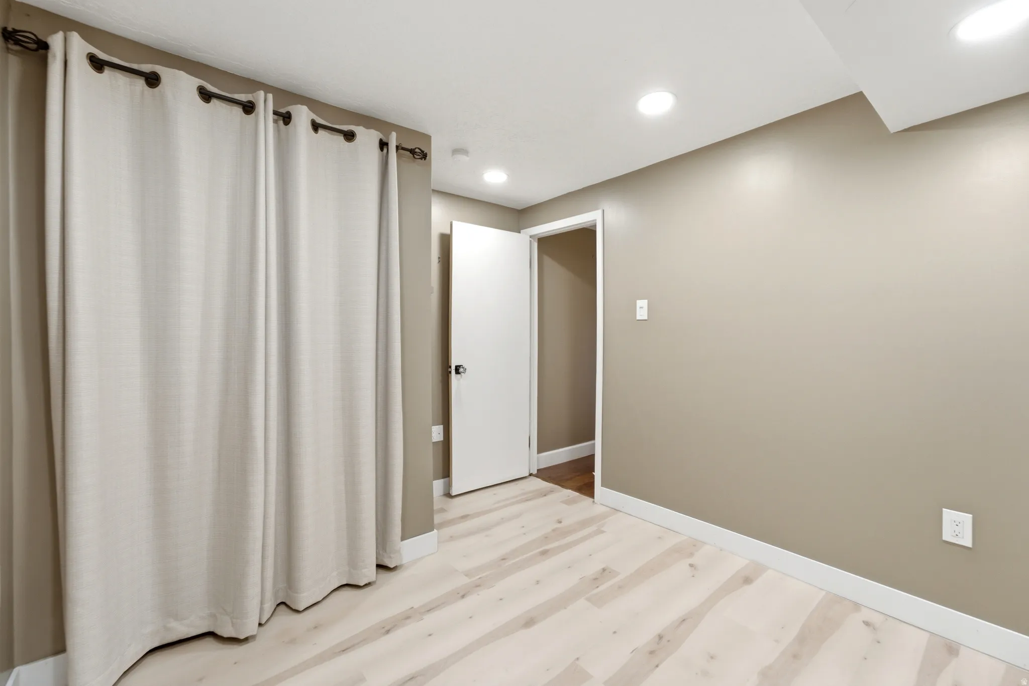 Light wood-finish flooring, recessed ceiling lighting, and neutral wall tones