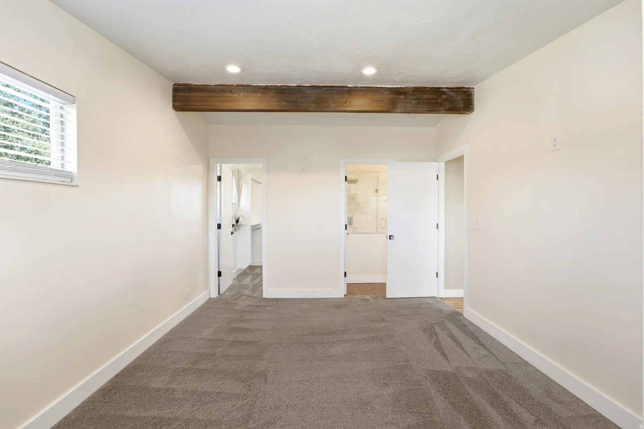 Exposed wood beam, recessed lighting, carpeted flooring, window with blinds, and white interior doors
