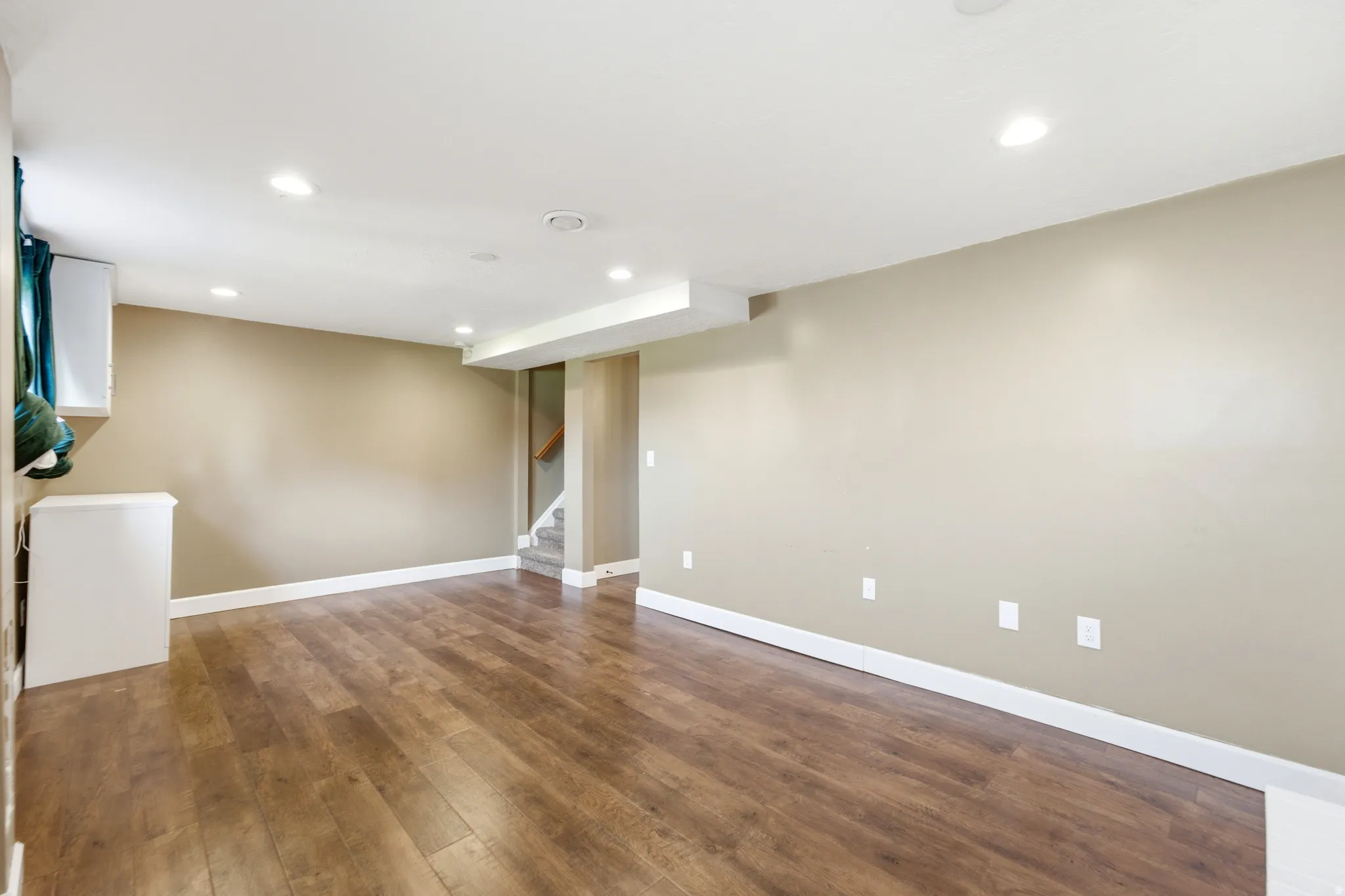 Recessed lighting, wood-finish flooring, neutral wall tones, white trim, and a built-in white cabinet