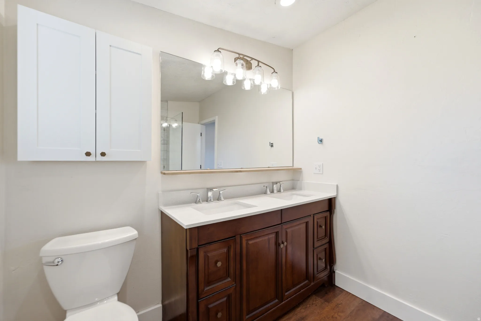 Dual sink vanity with dark wood-finish cabinetry, white countertops, and brushed nickel faucets