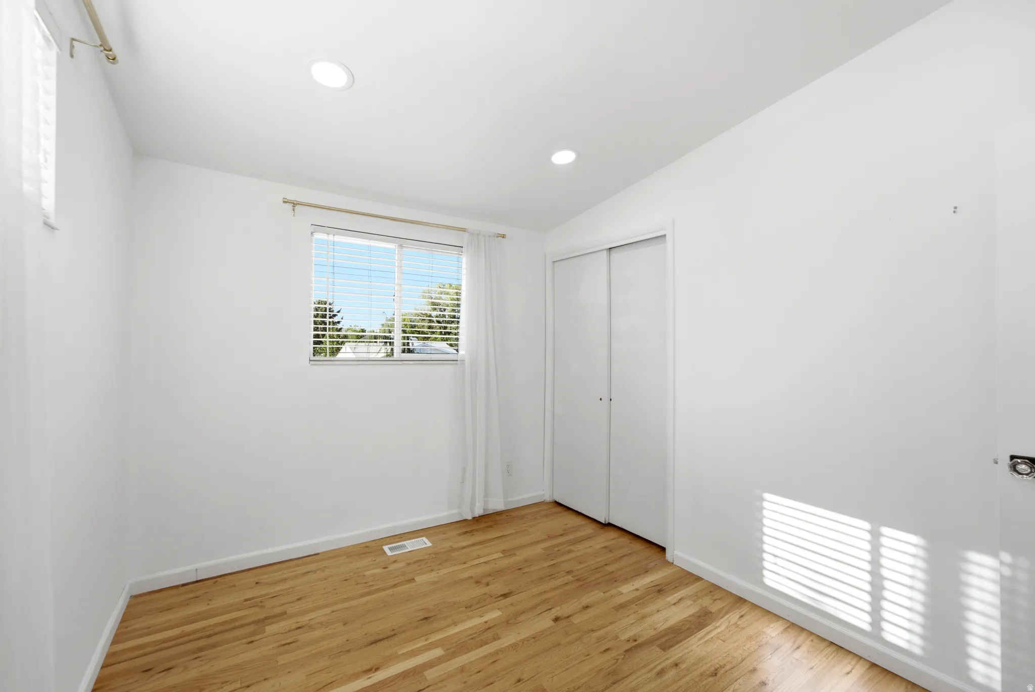 Recessed lighting, wood-finish flooring, and a window with blinds