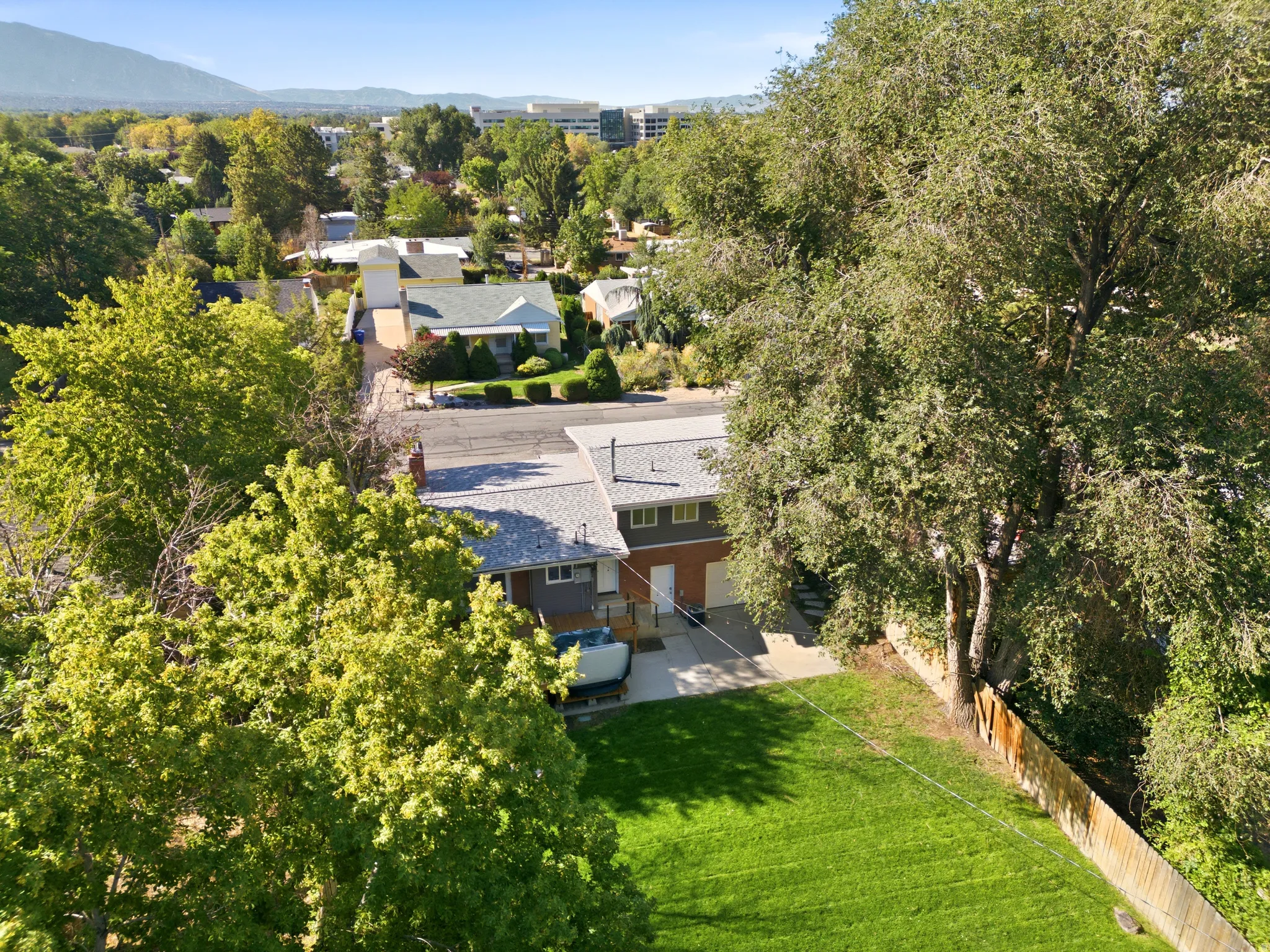 Expansive green lawn with mature trees and a wood-panel fence