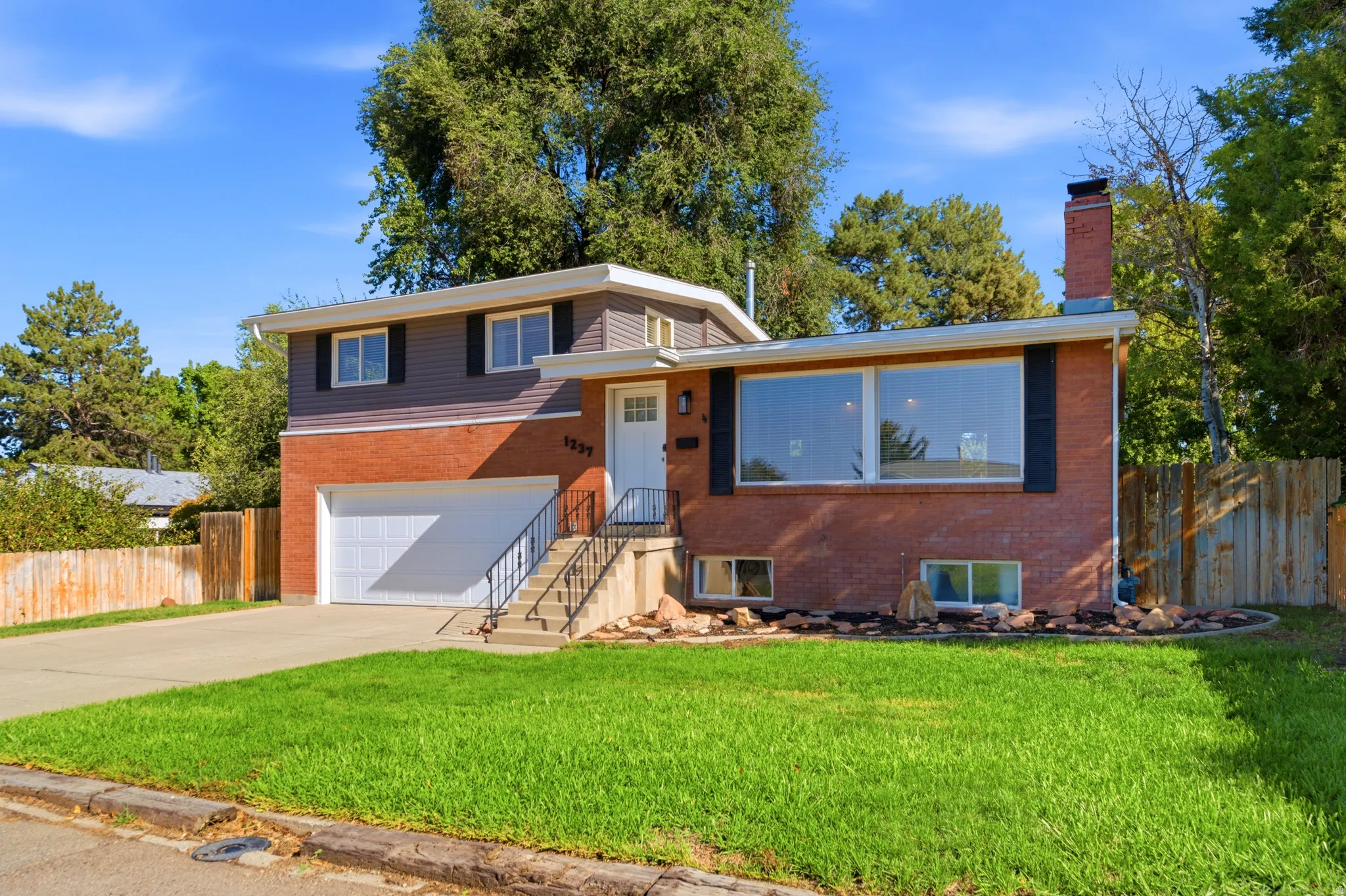 Brick and siding exterior with a concrete driveway, attached garage, and a front lawn