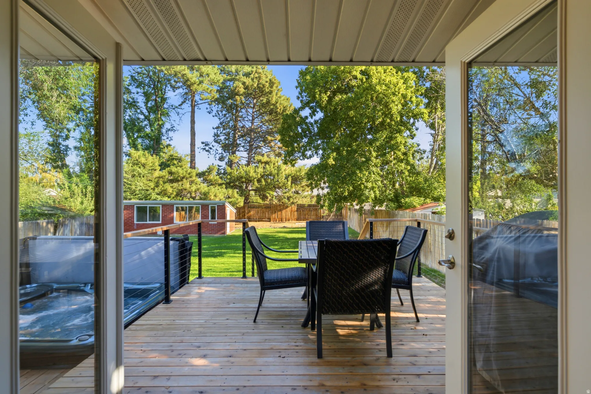 Expansive wood deck with cable railing and a built-in hot tub