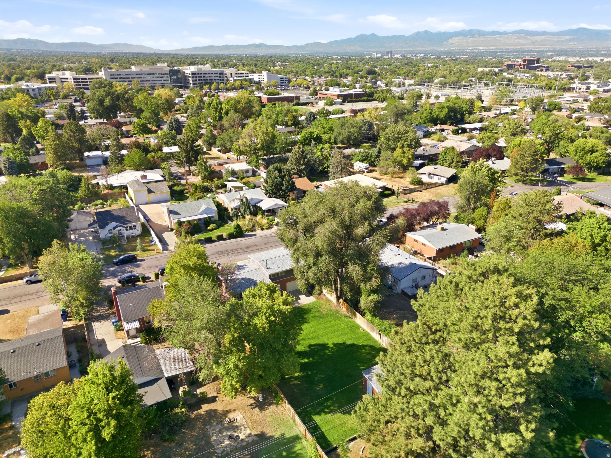 Expansive lot featuring a vibrant green lawn within a residential neighborhood, surrounded by mature trees
