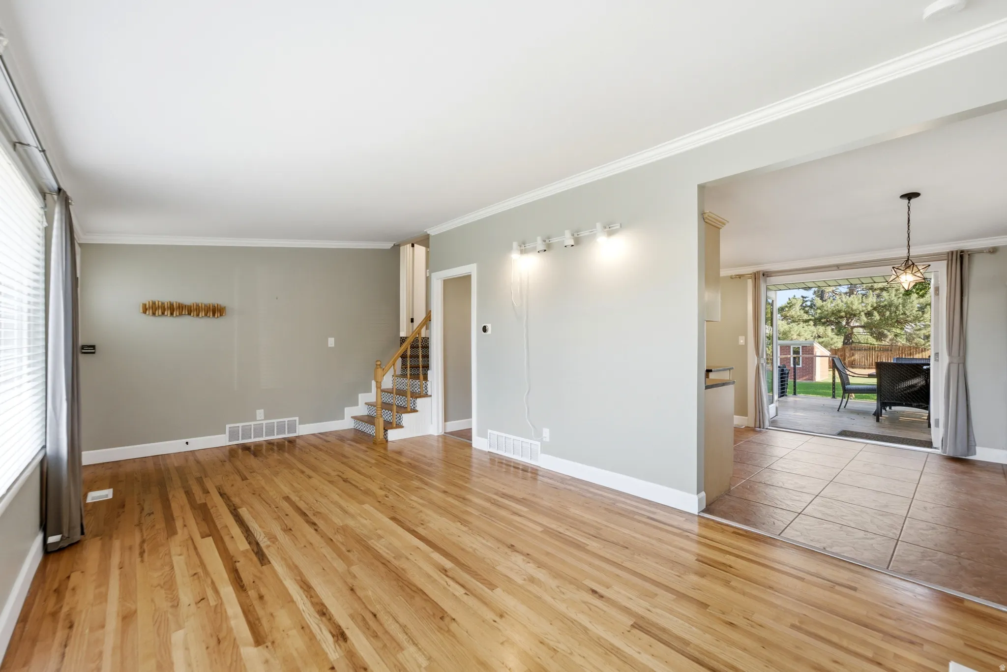 Hardwood flooring, crown molding, a built-in staircase, sliding glass doors, and a patio with an outdoor structure