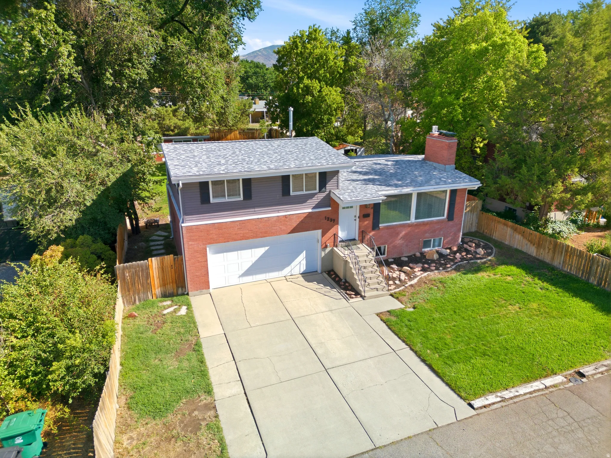 Property exterior featuring a brick and siding facade, attached garage, concrete driveway, and front lawn
