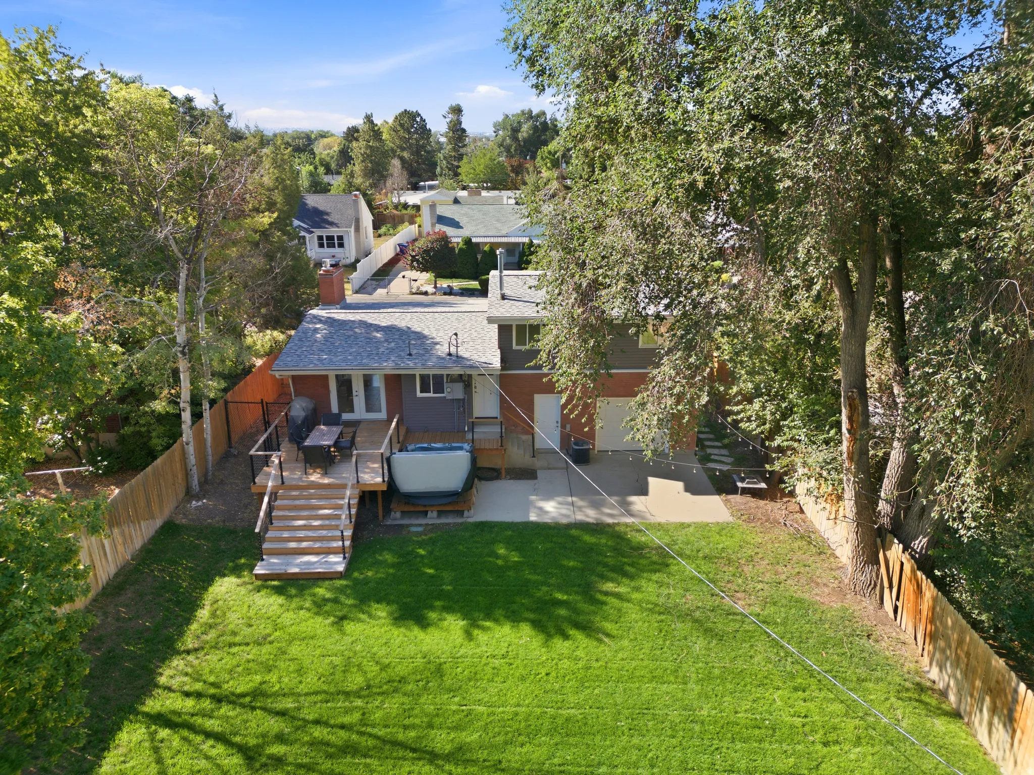 Expansive green lawn, elevated wooden deck, and concrete patio