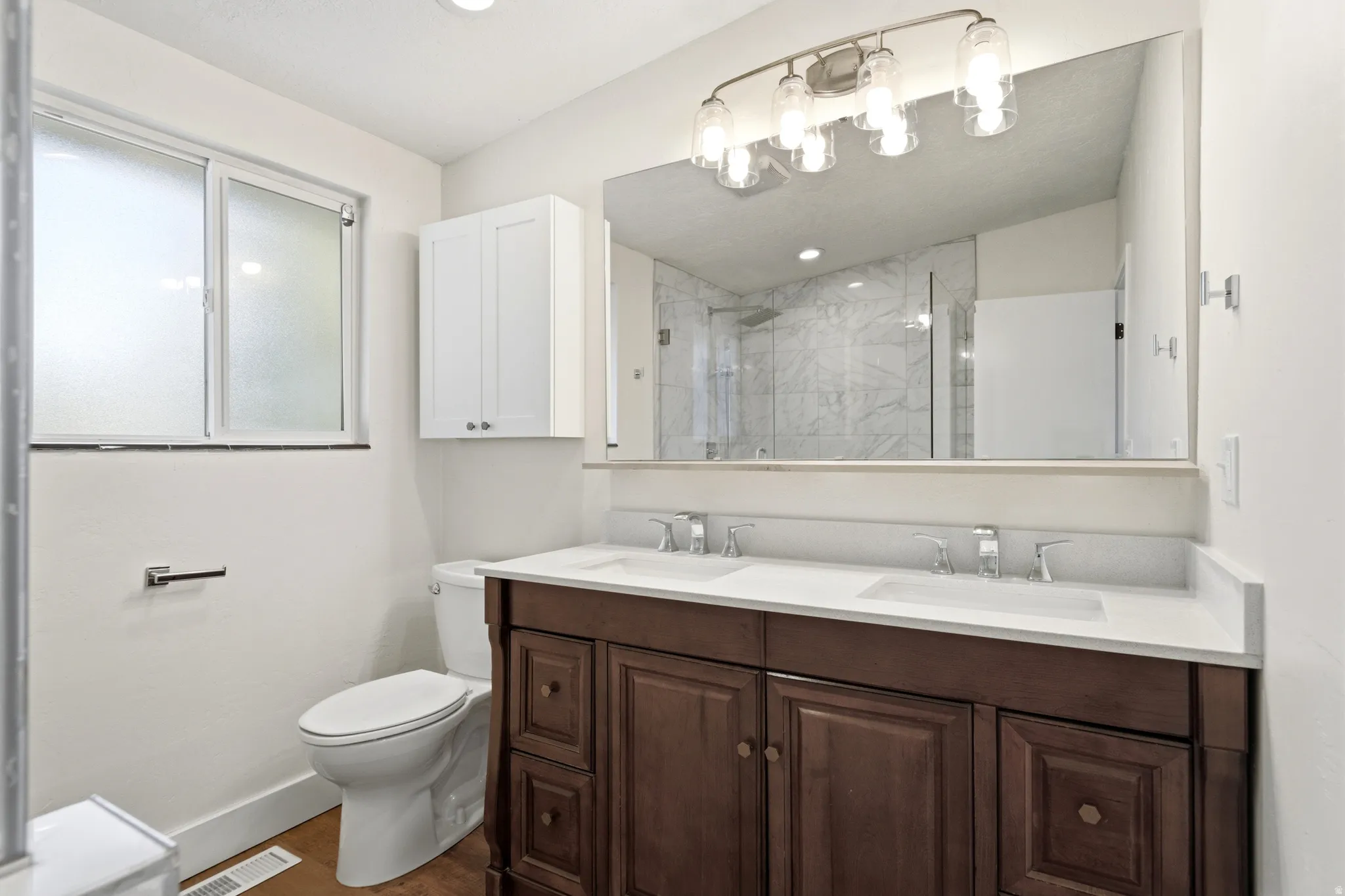 Dual vanity with white countertop, chrome fixtures, and dark wood-finish cabinetry