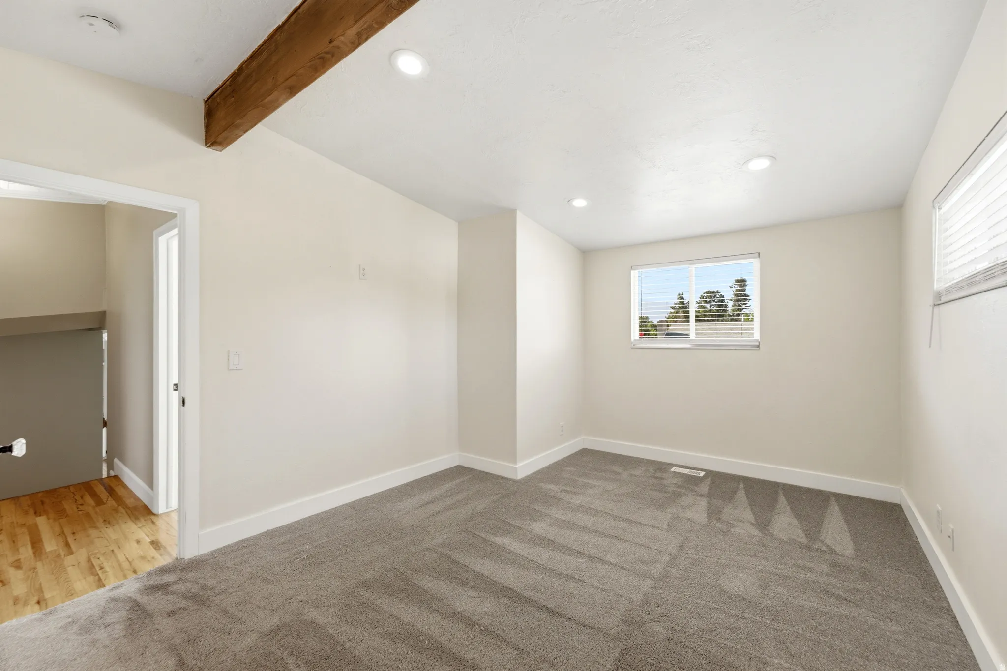Recessed lighting, wood beam ceiling accent, carpeted flooring, window with blinds, and white trim