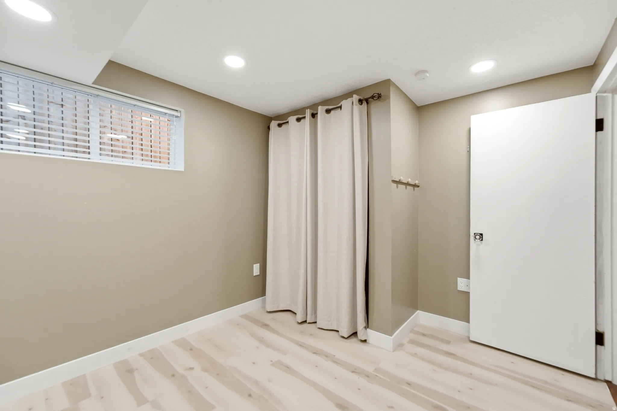 Recessed lighting, light wood-finish flooring, white trim, and a window with blinds