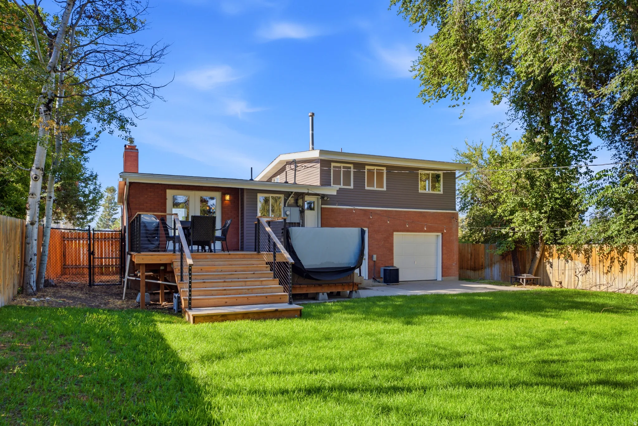 Expansive grass lawn with a multi-level deck featuring wood stairs and black metal railings