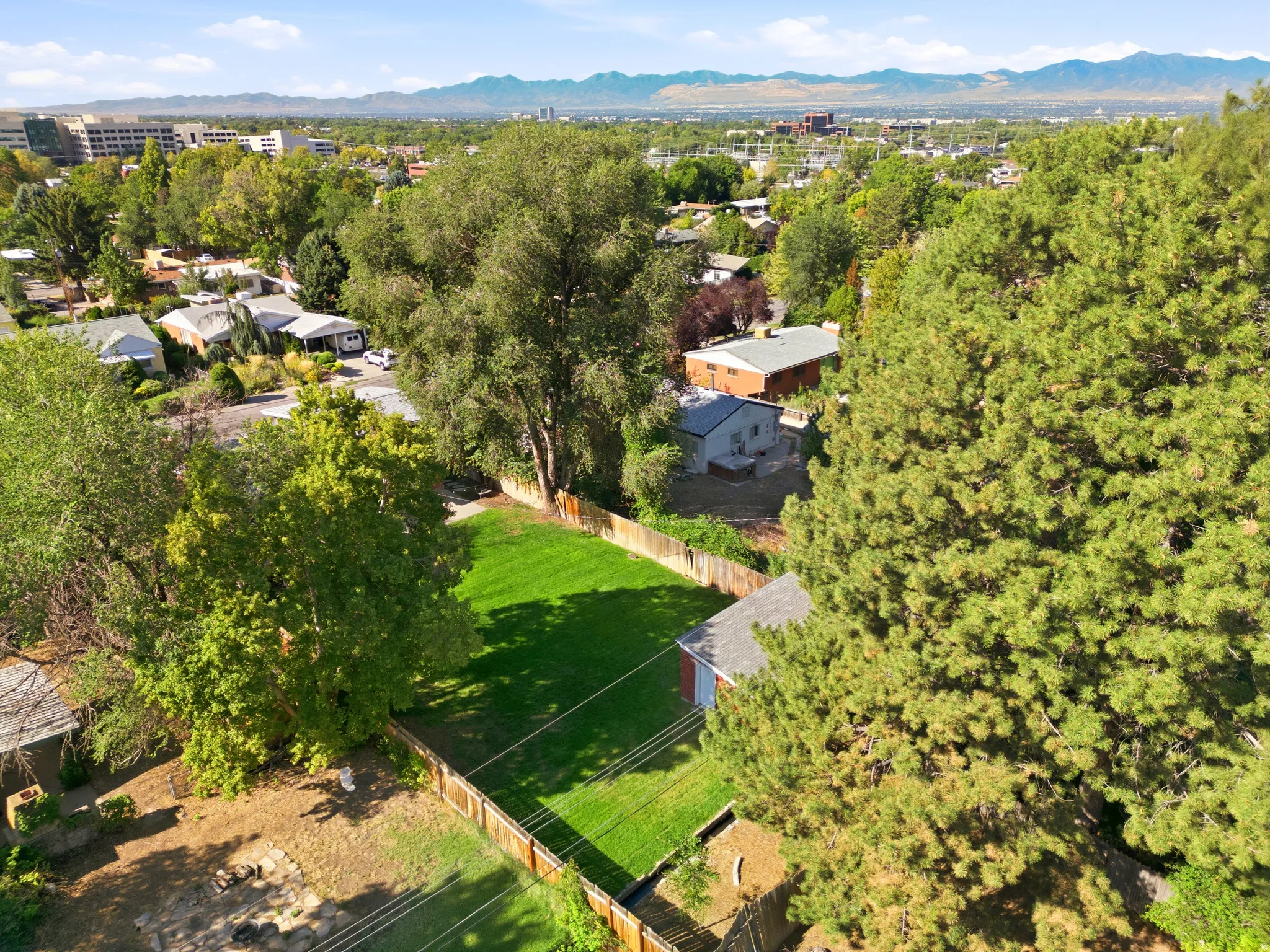 Expansive green lawn with mature trees and a wood fence