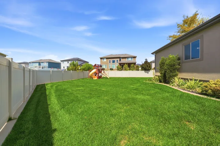 Expansive grass lawn, vinyl perimeter fencing, stucco exterior, and well-maintained landscaping