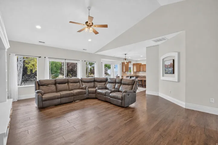 Vaulted ceiling with a ceiling fan, recessed lighting, wood-finish flooring, and multiple windows