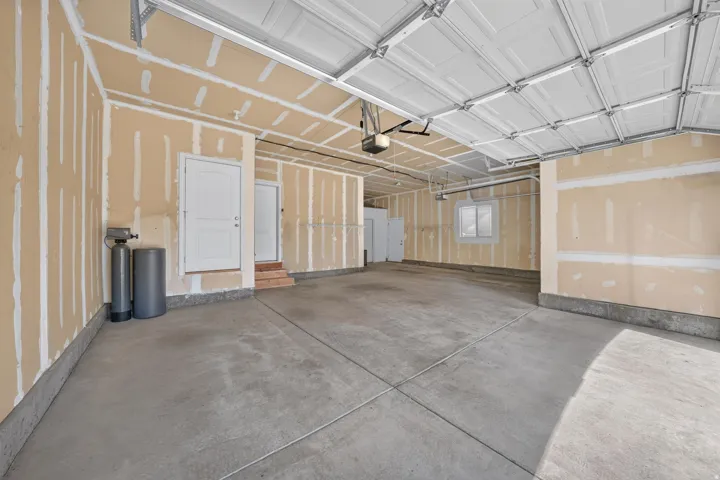 Spacious garage with concrete flooring, automatic garage door opener, and interior access doors