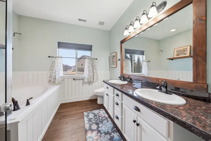 Primary bathroom with dual sinks, walk in shower, and jetted tub