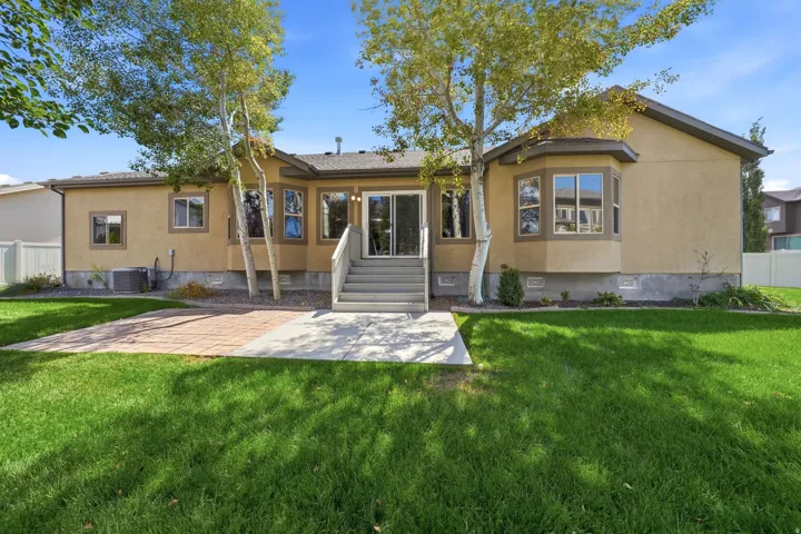 Rear exterior featuring a stucco finish, multi-pane windows, a sliding glass door, a bay window, and a paver patio