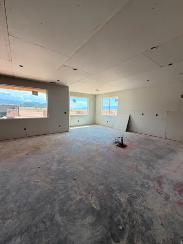 Spacious room with multiple windows, drywall-finished walls and ceiling, and exposed concrete flooring