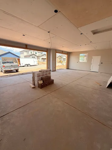 Concrete flooring with expansion joints, exposed drywall ceiling, and a white interior door