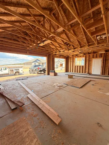 Unfinished garage space with exposed wood framing, concrete flooring, and a single window opening