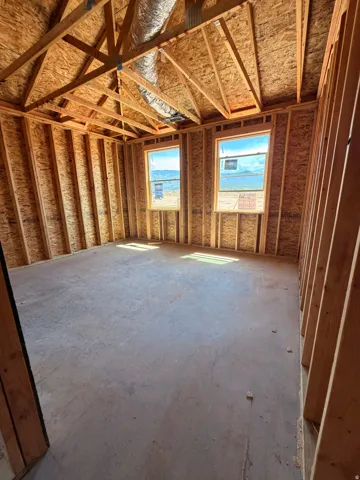 Exposed framing with structural elements, concrete flooring, and two windows