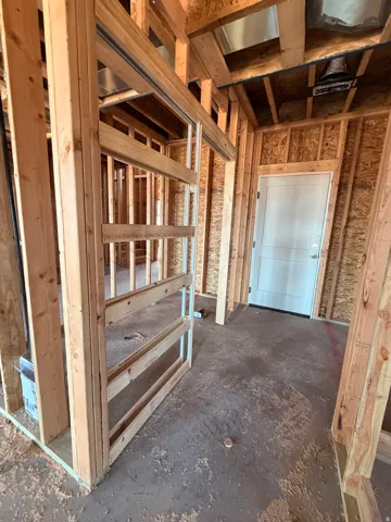 Framed interior with visible structural elements, including wood stud walls and ceiling joists