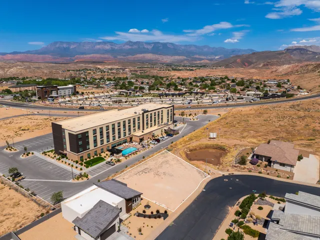 Vacant land parcel featuring a paved road, mountain backdrop, and surrounding desert landscaping