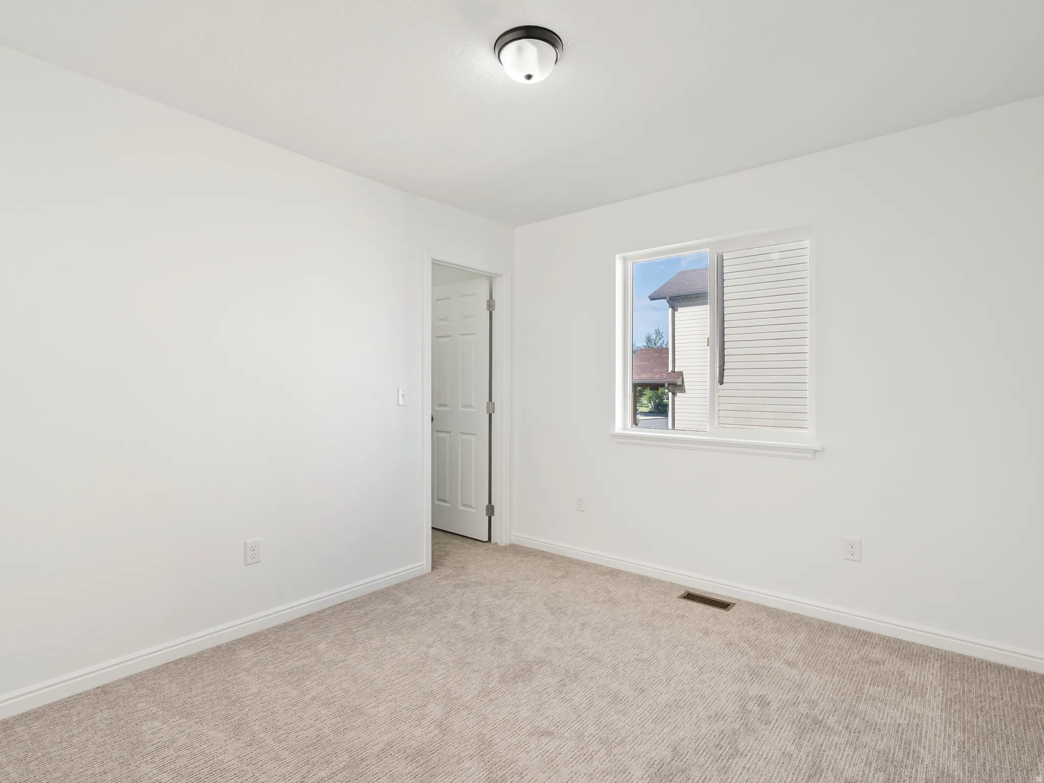 White-painted interior walls, light-colored carpet, white trim throughout, and a single window with blinds