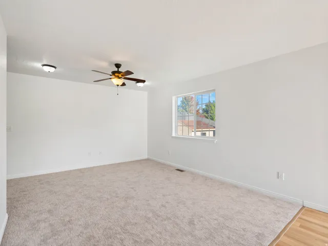 Neutral tone wall paint, carpet flooring, ceiling fan with integrated lighting, recessed lighting, and a single-pane window
