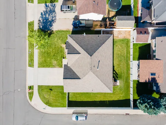 Corner lot residence with a shingled roof, extensive concrete driveway, and surrounding green lawn