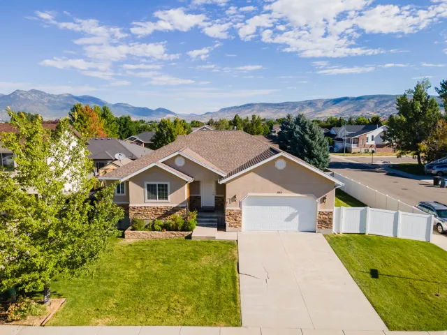Stucco exterior with stone accents, attached two-car garage, concrete driveway, and front yard landscaping
