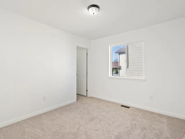 White-painted interior walls, light-colored carpet, white trim throughout, and a single window with blinds
