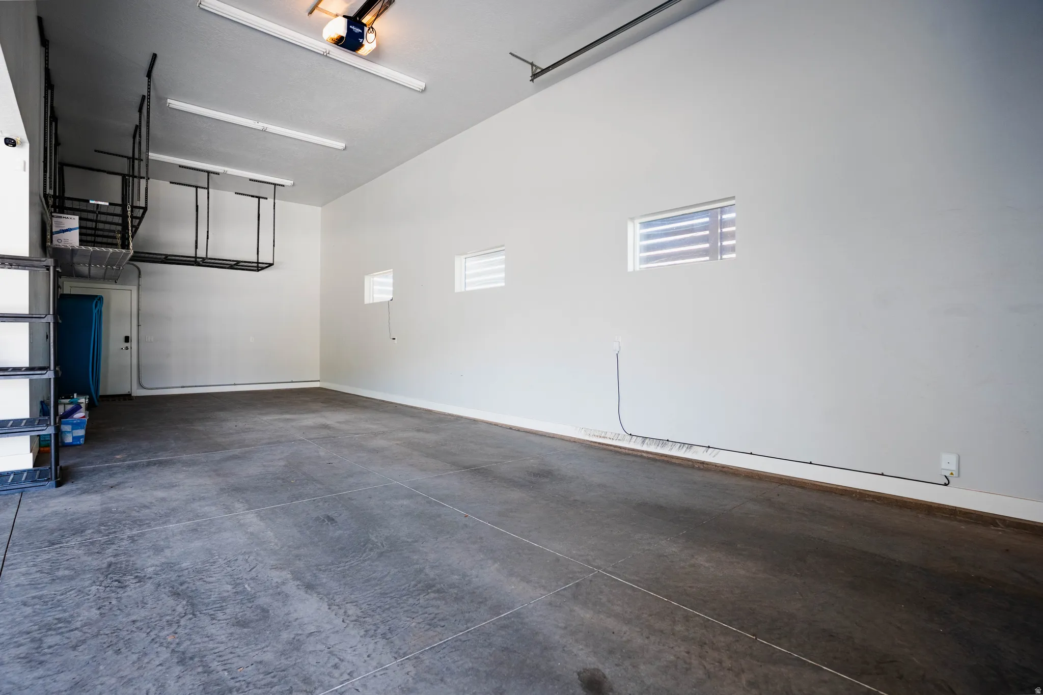 Spacious garage featuring high ceilings, overhead storage racks, integrated lighting, and multiple windows