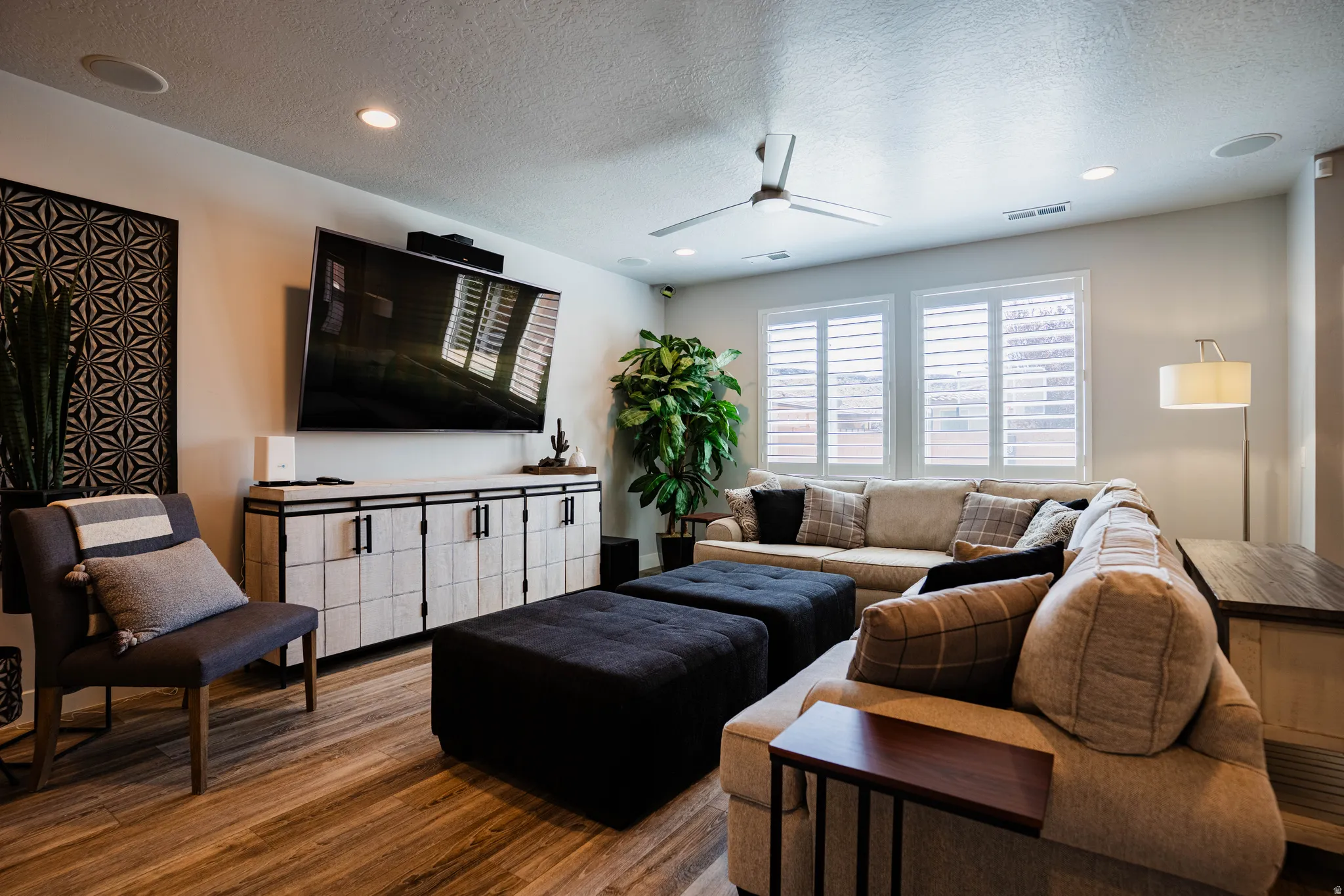 Wood-finish flooring throughout, recessed lighting, ceiling fan, built-in entertainment console, and window shutters