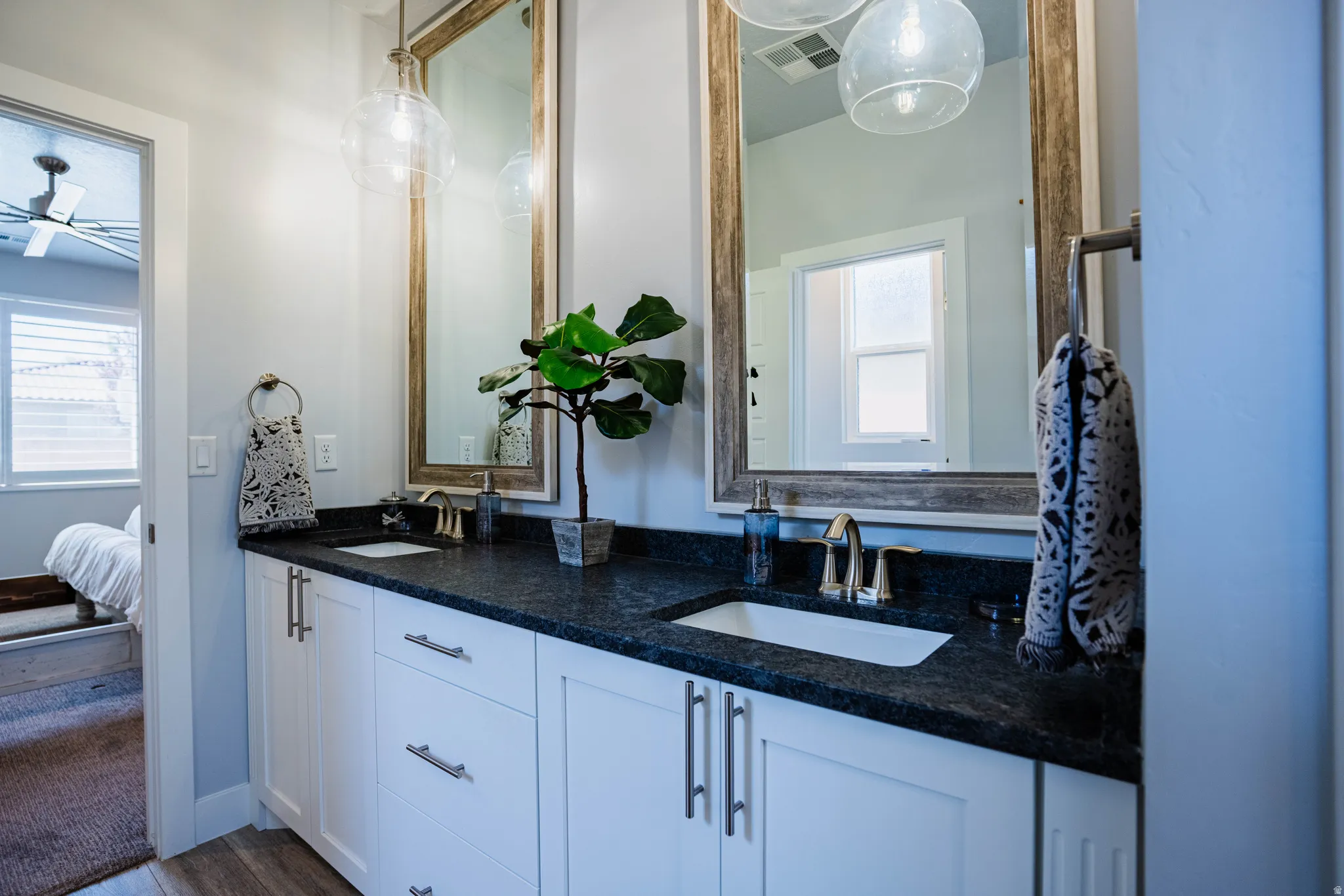 Double vanity with white cabinetry, dark countertop, and two framed mirrors
