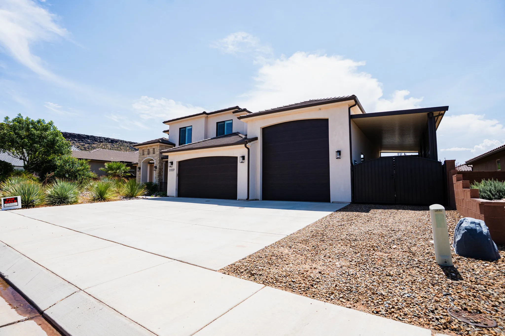 Stucco exterior with a tile roof, an arched entry, a two-car garage, and an attached carport