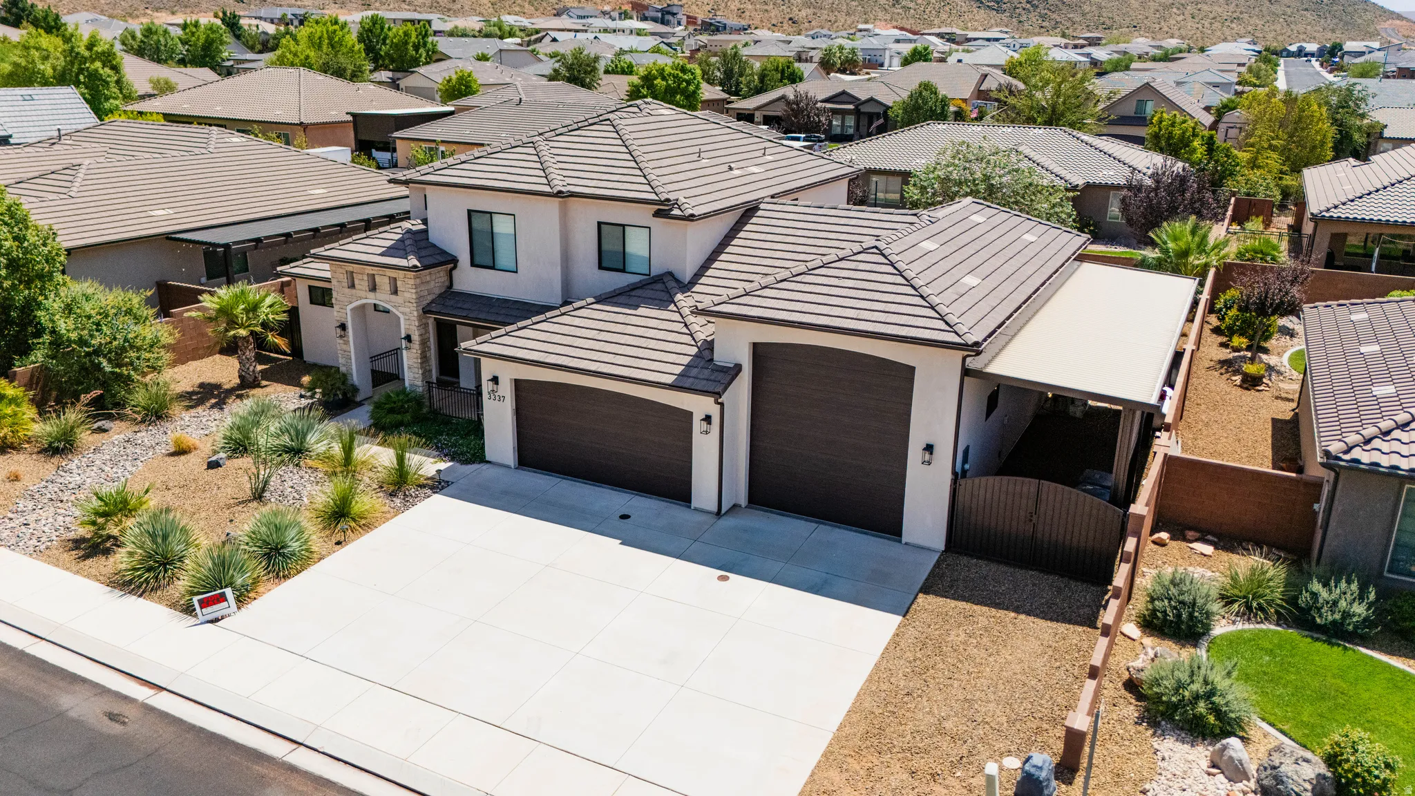 Two-story stucco exterior, tile roof, dual garage doors, desert-style landscaping, and an enclosed side patio