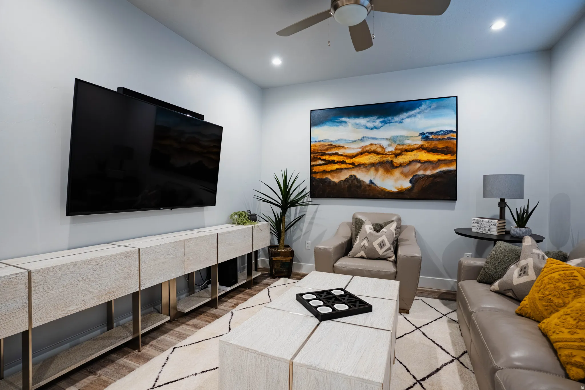 Recessed lighting, ceiling fan, wall-mounted television, built-in entertainment console, and wood-finish flooring