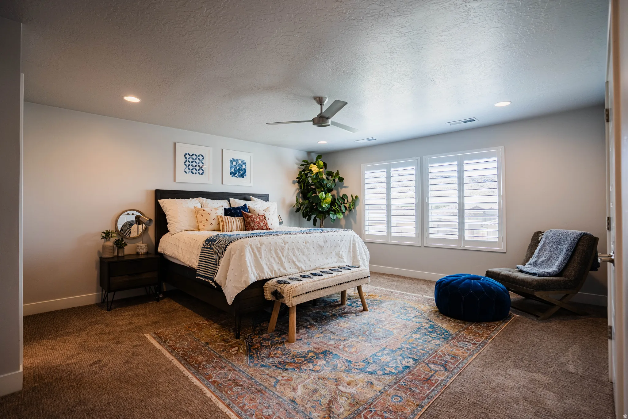 Recessed lighting, ceiling fan, two windows with plantation shutters, and carpeted flooring