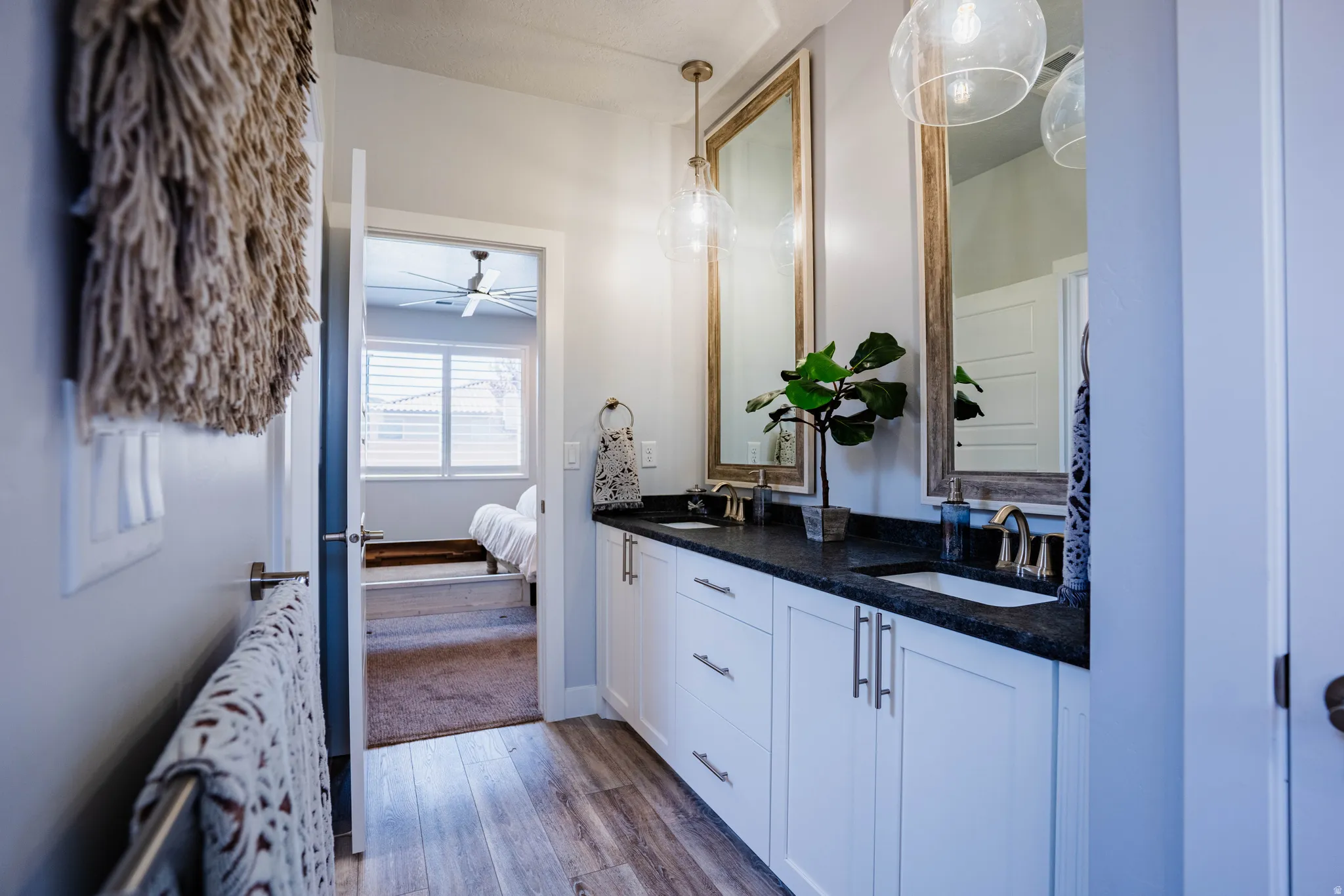 Double vanity with dark countertops and integrated sinks, individual framed mirrors, and pendant lighting