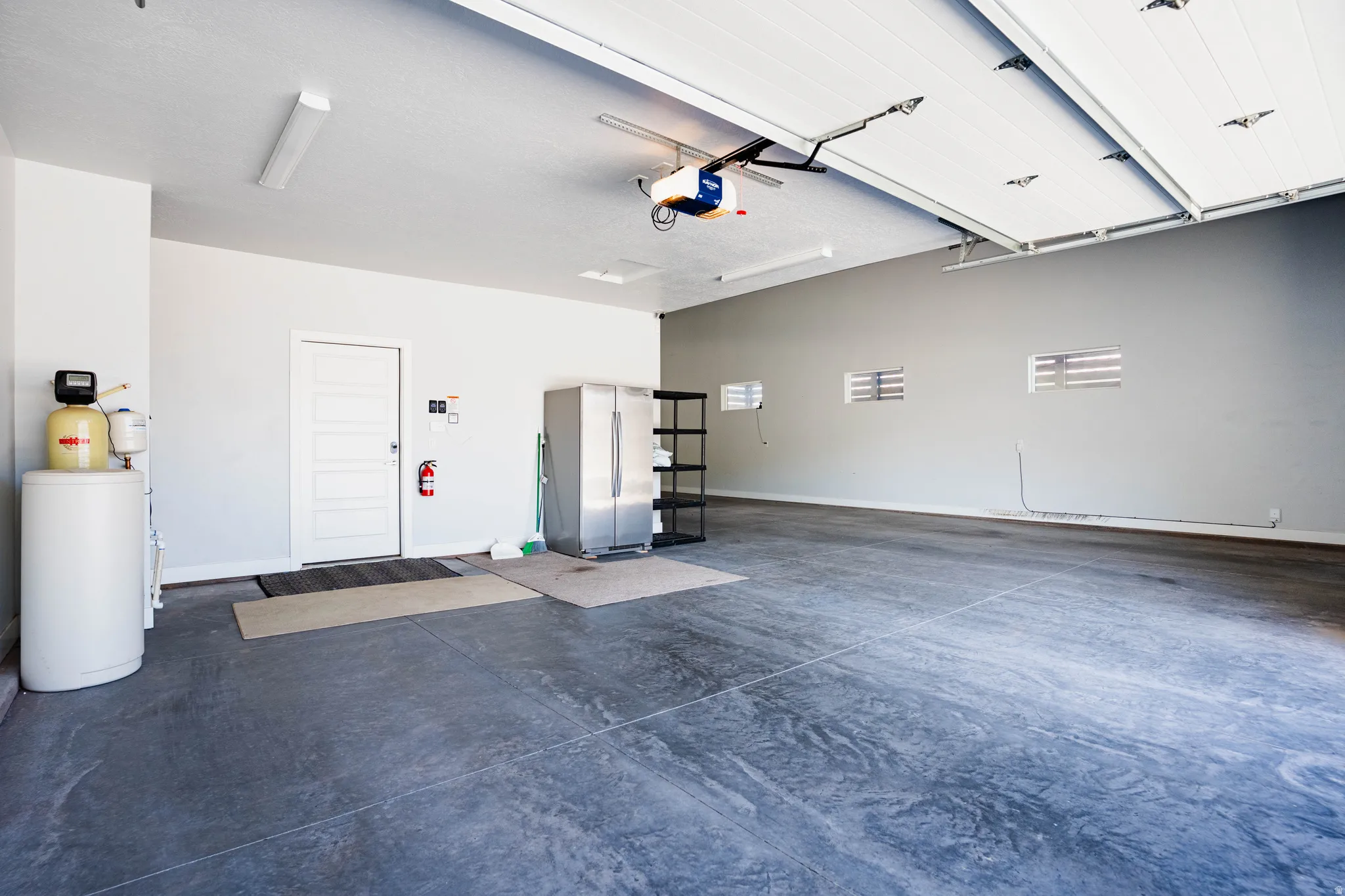 Spacious garage featuring a concrete floor, overhead lighting, and an automatic garage door opener