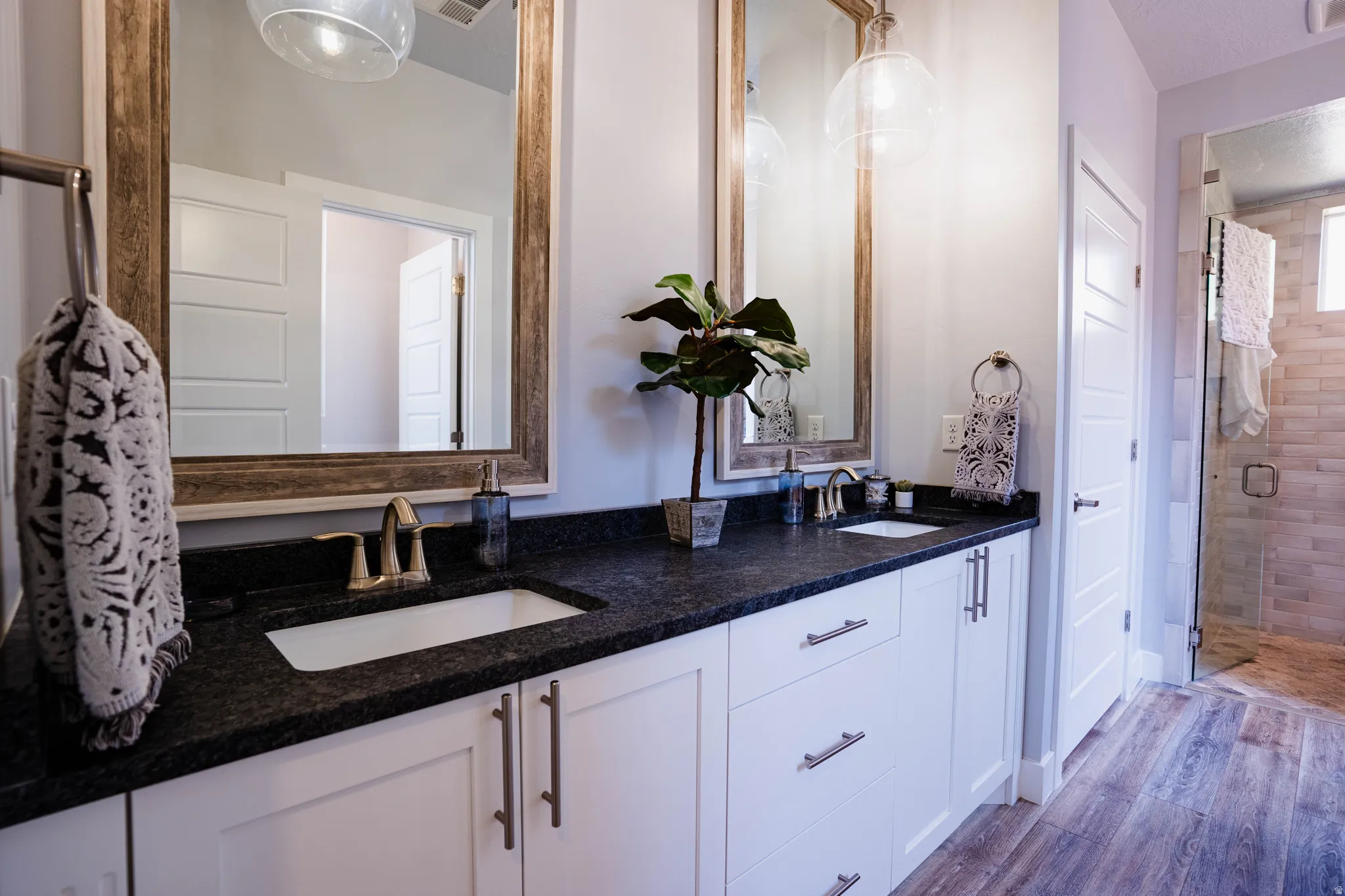 Dual vanity with dark stone countertop, undermount sinks, and bronze-finish fixtures
