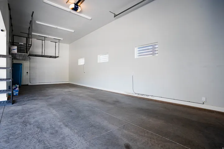 Spacious garage featuring high ceilings, overhead storage racks, integrated lighting, and multiple windows
