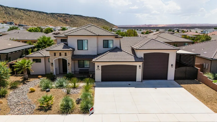 Stucco exterior with stone accents, concrete driveway, tiled roofing, and desert landscaping