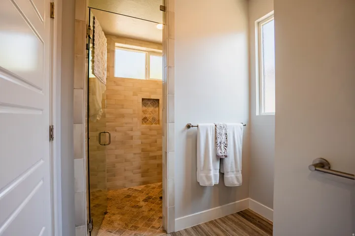 Glass-enclosed shower with subway tile walls, a decorative tile niche, and a patterned tile floor
