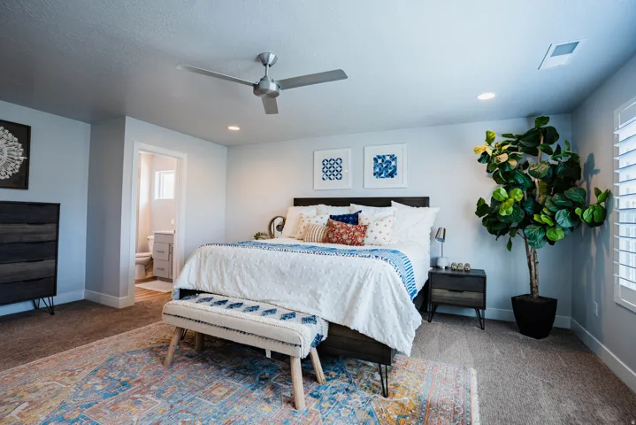 Recessed lighting, ceiling fan, carpet flooring, a built-in window shutter, and an open doorway to a bathroom with a window